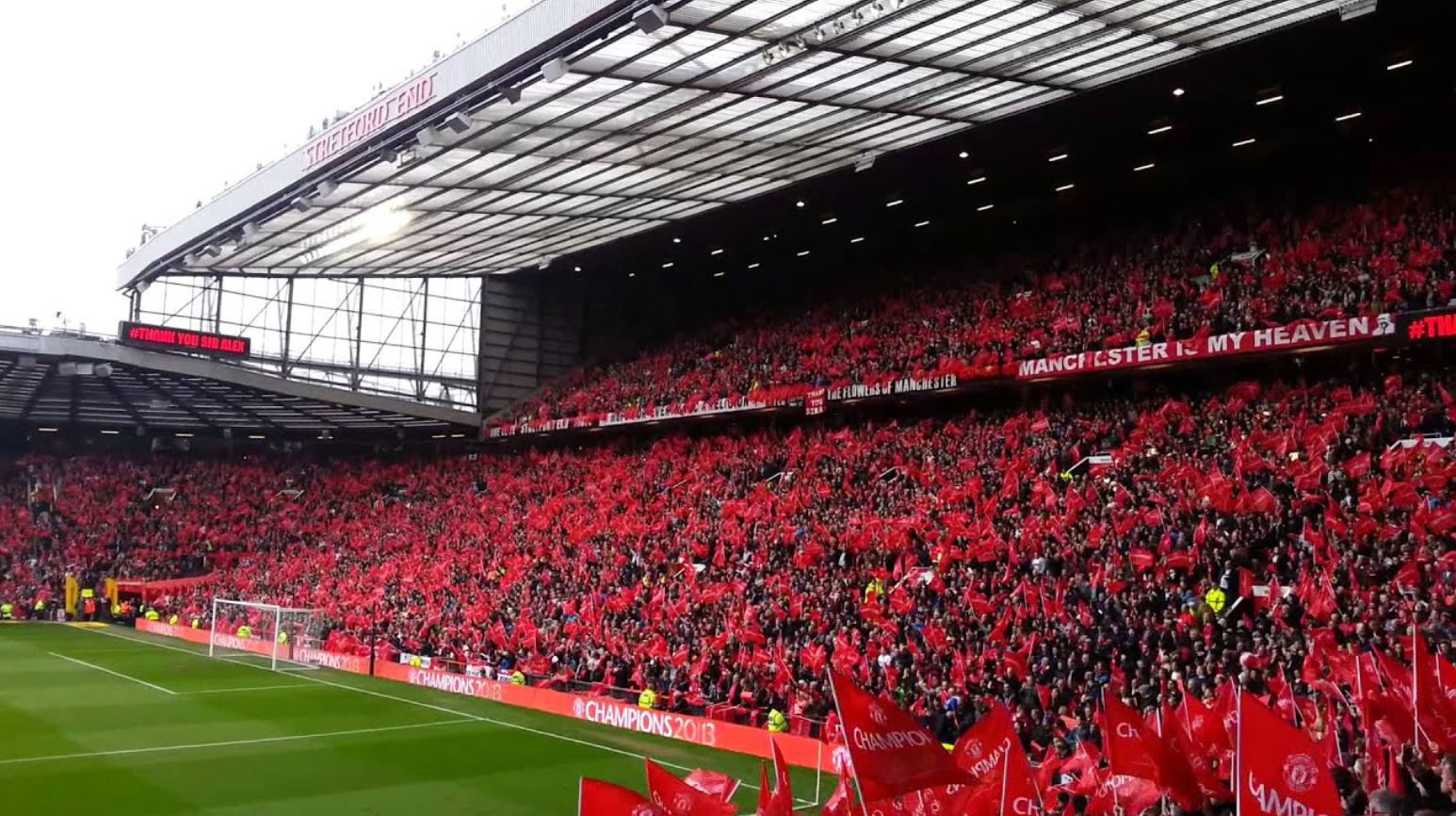 Image from the inside of the 
                Old Trafford stadium, home of the Manchester United team, showing the supporters with red flags during a match.