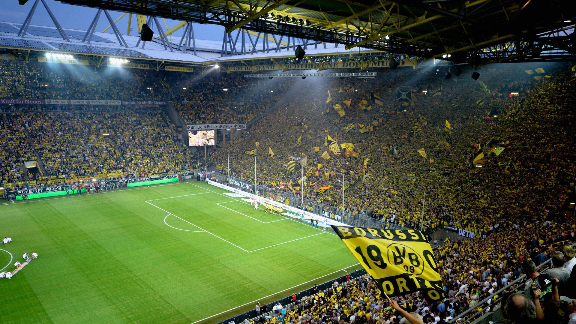 Image from inside 
                the Signal Iduna Park stadium, home of the Borussia Dortmund team, showing the supporters with yellow flags during a match.